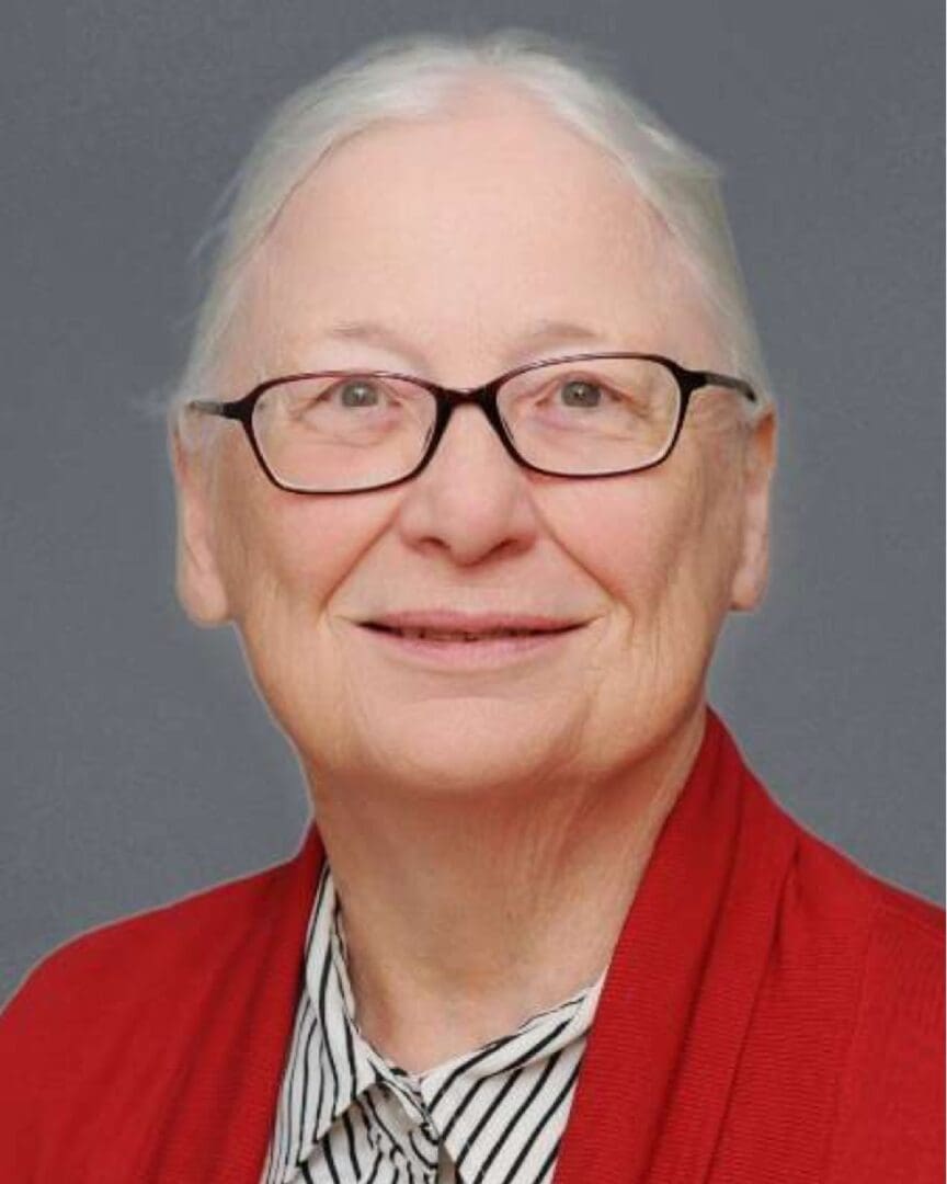 An older woman wearing glasses and a red sweater.